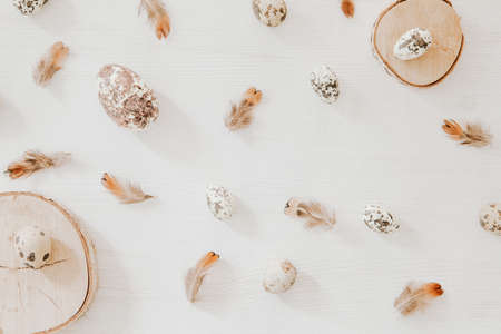 Easter pattern from little eggs and wooden blocks on white background with feathersの写真素材