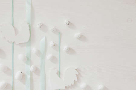 Blue ribbons on white wooden background with little easter eggs and roosterの写真素材