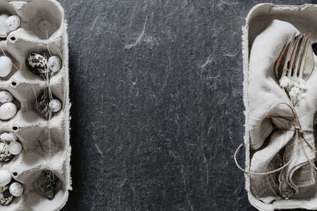 Easter table setting with napkin and egg box on the sides of black stoneの写真素材