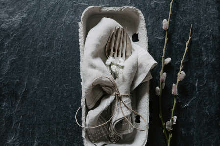 Natural Easter table decoration with silverware in egg box on black stone with fluffy willowの写真素材