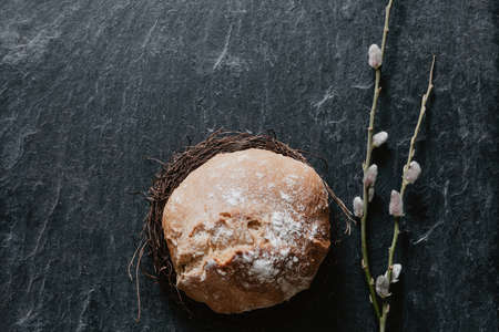 Bread lying in a  wreath with fluffy willow on black stoneの写真素材