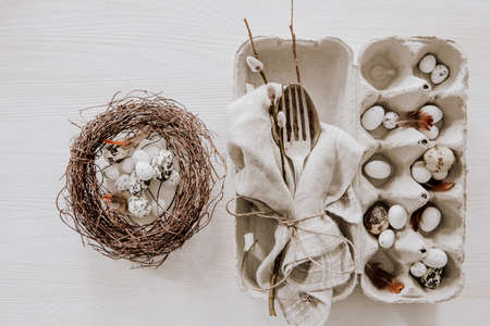 Natural Easter table decoration with silverware and eggs in a wreath on wooden tableの写真素材