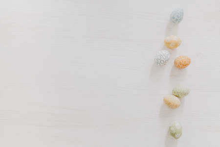 Pastel Easter eggs on white wooden table, flat layの写真素材