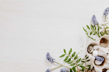 Natural Easter decoration with eggs in a egg box and grape hyacinths with gypsophila paniculata in the corner of white wooden backgroundの写真素材