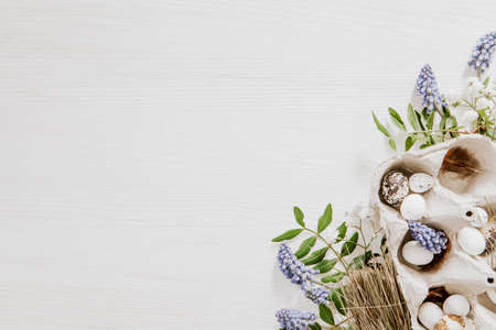 Simple Easter decoration with eggs box and grape hyacinths with gypsophila paniculata in the corner of white wooden backgroundの写真素材