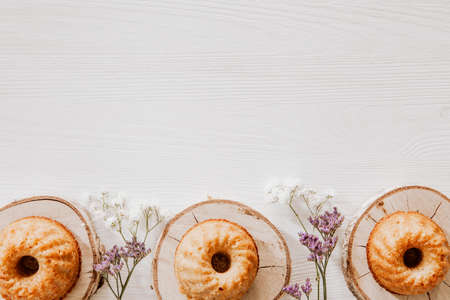 Muffins on wooden blocks lying on wooden table with violet and white flowersの写真素材