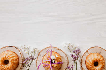 Wooden blocks with cupcakes, violet and white flowers on the bottom of white wooden backgroundの写真素材