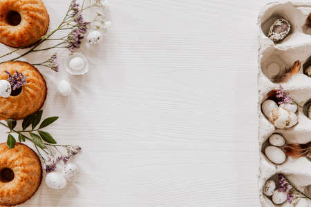 Muffins with eggs, white and violet flowers on wooden table with egg boxの写真素材