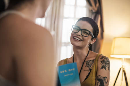 Attractive young adult Caucasian female with tattoos holds a travel brochure in her hands and smiles...