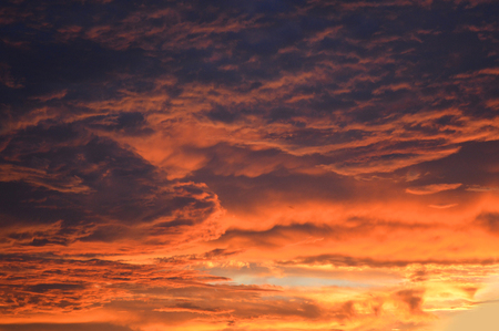 Dark stormy cloudy sky scary dramatic orange clouds at sunsetの写真素材