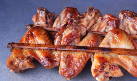 grilled chicken wings / roast BBQ chicken wings with garnish in bamboo stick thai style chicken grilledの写真素材