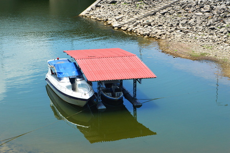 houseboat raft floating on reservoir river / speed boat with red roof on hydroelectric damの写真素材
