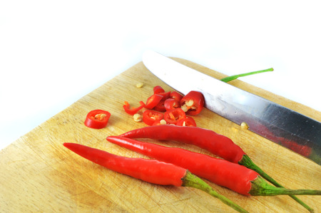 slicing Chili pepper / red chili cut with knife on wood block for food on white backgroundの写真素材