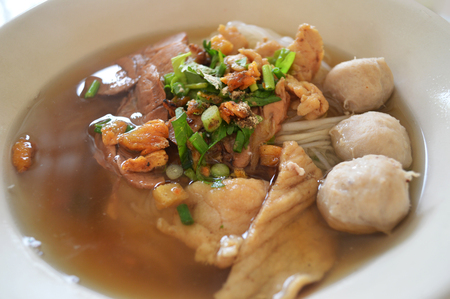 delicious noodles bowl / close up of rice noodles soup with meatball pork stew and vegetable in bowl traditional thai and chinese style food of asiaの写真素材