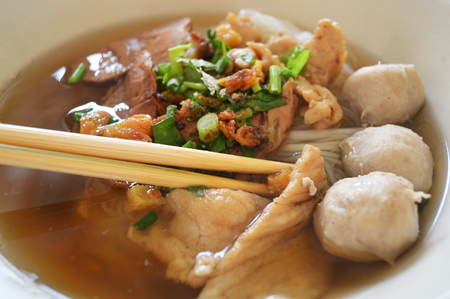 delicious noodles bowl chopsticks / close up of rice noodles soup with meatball pork stew and vegetable in bowl traditional thai and chinese style food of asiaの写真素材