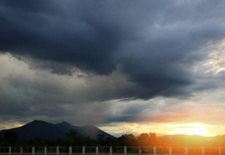 rainy storm season / it's raining on hill and storm clouds sunset on the mountain backgroundの写真素材