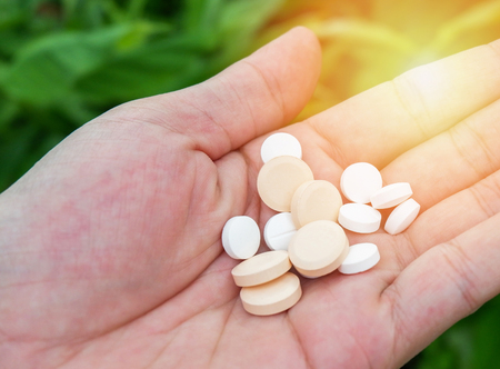 pills and medicines in the hand nature green leaf background / herb extract natural medicine pills - healthy eating with natural product herbal nourish the bodyの写真素材