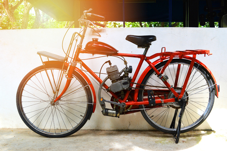old motorcycle bicycle / vintage bicycle red on wall classic engine bike in garage ancient bicycleの写真素材