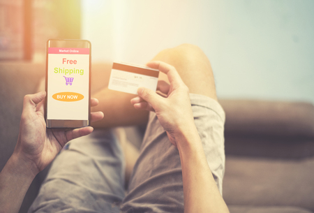 online shopping concept / young man using smartphone shopping in website market online and hands holding credit card on the bed - comfortable relax happy shopping online holiday at homeの写真素材