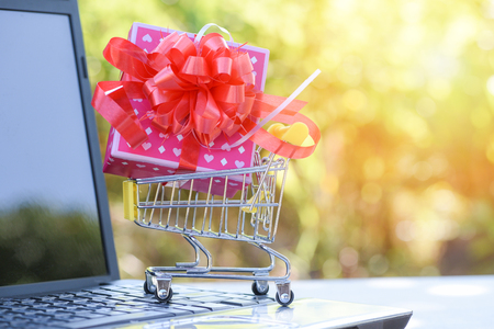Valentines day shopping and Gift Box / Pink present box with red ribbon bow on shopping cart concept Merry Christmas Holiday Happy new year or Valentines day on Laptop outdoors - Shopping onlineの写真素材
