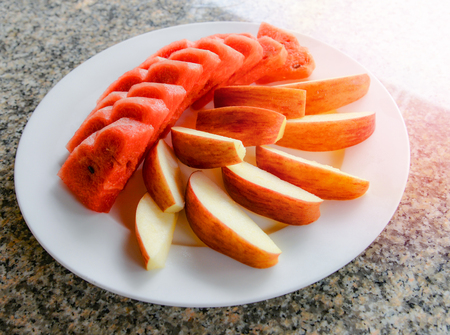 fruit on plate top view / fresh fruit watermelon and apple slice on white plate on dining tableの写真素材