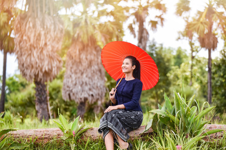Women asia farmer in field / Portrait of beautiful young asian woman happiness smile hold umbrella in hand sitting agriculture area in countryside village rustic - Life young girl dress tribeの写真素材