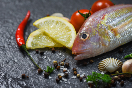 Seafood fish plate ocean gourmet dinner fresh raw fish with herbs and spices on dark background