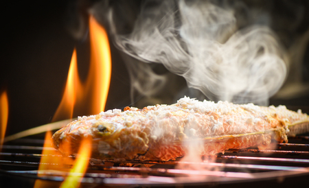 Fish on grill / Close up of seafood grilled fish food with salt on the grill fire and smoke on dark backgroundの写真素材