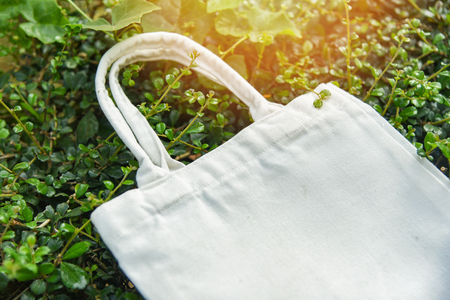 White tote canvas fabric eco bag cloth shopping sack on green leaf nature background / Zero waste Use less plastic say no plastic bag pollution problem conceptの写真素材