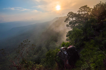 Wonderful landscape sunrise mountain with fog mist yellow and blue sky rising sunshine in the morning on hill top view jungle with rock on cliff tropical forestの写真素材