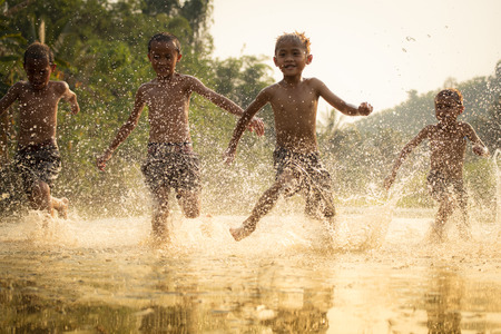 Asia children on river / The boy friend happy funny playing running in the water in countryside of...