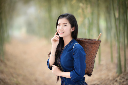 Asia women beauty skin in nature bamboo forest / Portrait of beautiful asian young girl happy smile with basket for harvest agriculture in countryside village - dress tribe lifeの写真素材
