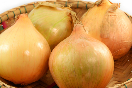 Onions in the basket isolated on white backgroundの写真素材