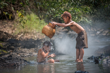 Asia children on river / The boy friend happy funny playing in the water stream in countryside of living life kids farmer rural peopleの写真素材