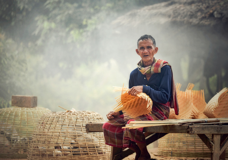 Asia life old man uncle grandfather working in home / Man elderly serious living in the countryside of life rural people in thailand weave bamboo basket craftsの写真素材