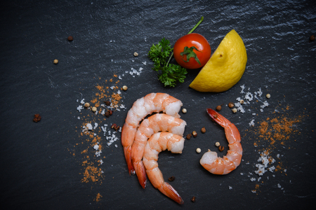 Seafood shrimp on top view / Shellfish fresh shrimps prawns ocean gourmet with tomato lemon green parsley herbs and spices on dark backgroundの写真素材