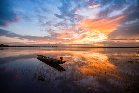silhouette fishing boat lake / beautiful sky with old wooden fishing boat sunset on river sunrise or sunset with colorful sky dramatic cloud backgroundの写真素材