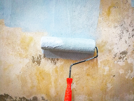 Renovate house / Hand painting old wall background with paint roller on building construction site interior decorationの写真素材