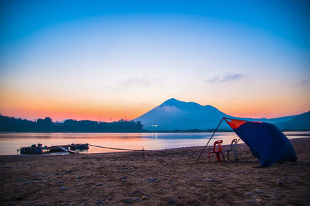 chair and umbrella canvas on river beach beautiful with colorful sky sunrise or sunset mountain background / Mekong Rive Asiaの写真素材