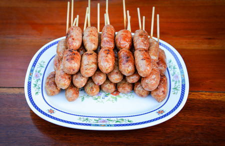 Fermented pork sausage grilled on plate in street food market thailandの写真素材