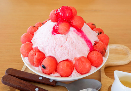 Bingsu sweet dessert shaved korea style / Friut bingsoo watermelon on ice topping with milk and berry syrup in tray on wood tableの写真素材