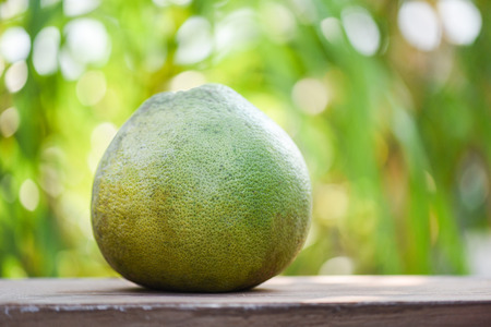 Fresh pomelo fruit on wooden table and green nature backgroundの写真素材