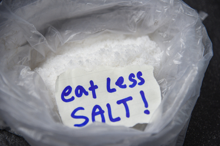 Eat less salt for health concept / Heap of salt in plastic bag backgroundの写真素材