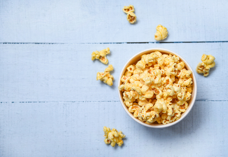 Popcorn in cup bowl and blue wooden  backgroubd top view / Sweet butter popcorn saltの写真素材
