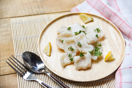 Japanese Cooked fish fillet piece with lemon and spices on wooden tray on dining table / pangasius...