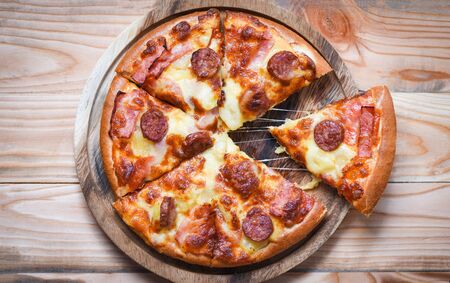 Pizza on wooden tray top view / delicious tasty fast food italian traditional pizza cheese with Mozzarella , Smoked pork sausage , Pineapple ham on topping sauceの写真素材