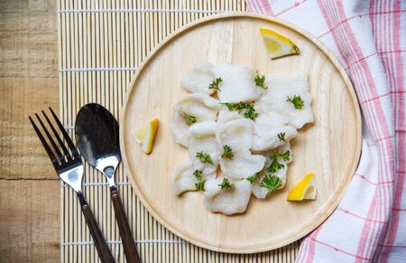 Japanese Cooked fish fillet piece with lemon and spices on wooden tray on dining table / pangasius dolly fish meatの写真素材