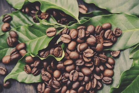Coffee beans on leaf / Roasted coffee on dark wooden table background - top view