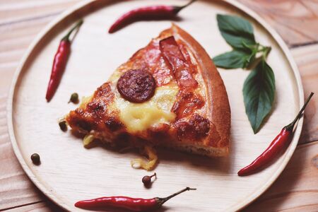 pizza slice on wooden tray delicious tasty fast food italian traditional pizza cheese with chili and spicesの写真素材