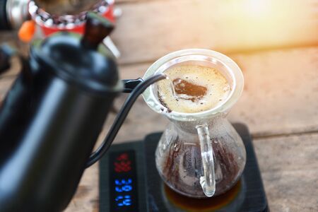 drip coffee barista pouring water on filtered brewing / make cup hand drip coffee in glass jar on...